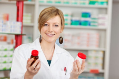 smiling pharmacist holding bottles of medicine